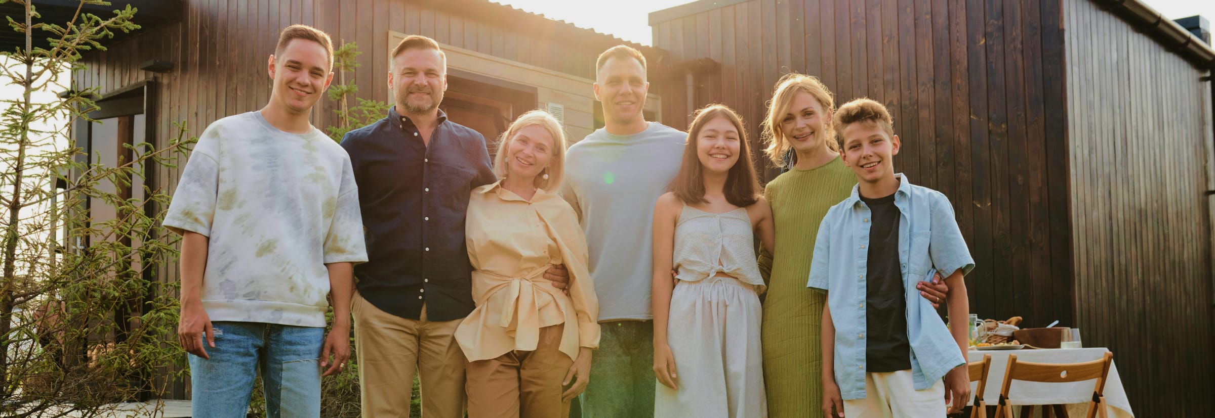 Lachende Familie und Freunde vor einer Holzscheune