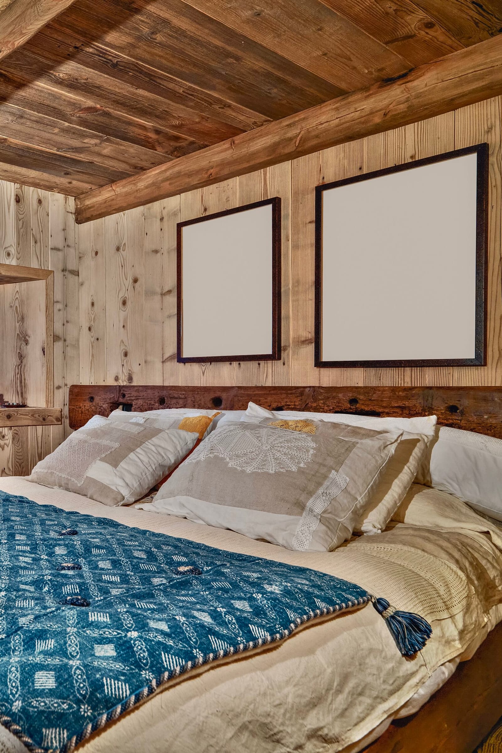 Bett mit gehäkelten Kissen vor einer Holzwand im neuen Apartment