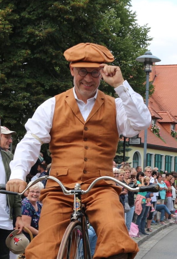 Rainer Schmidt in historischer Radfahrerkleidung mit Schiebermütze beim Festumzug