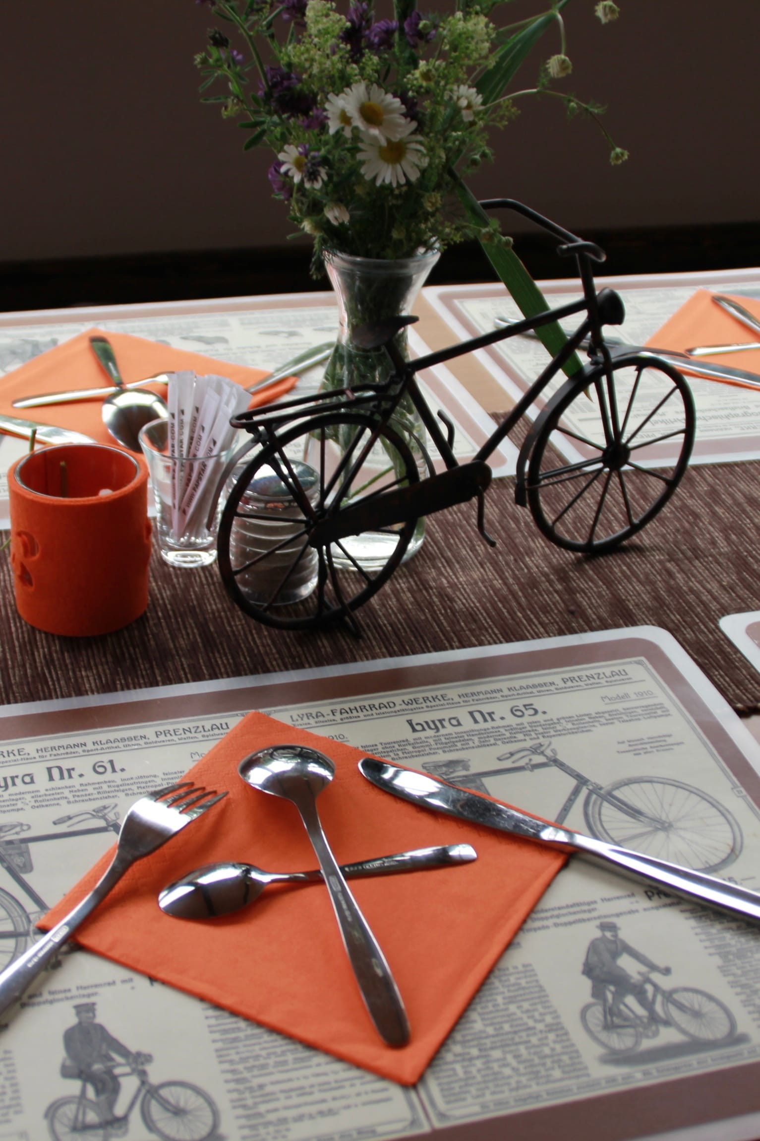 Gedeckter Tisch im Restaurant mit Fahrrad-Dekoration und Blumen