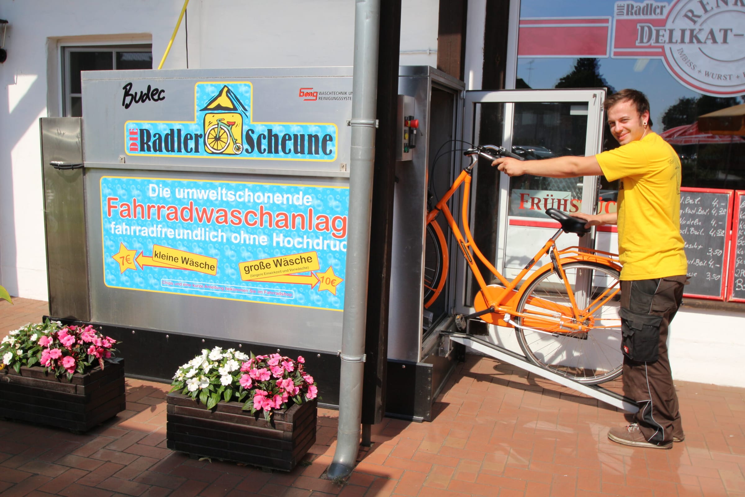 Mitarbeiter stellt ein Fahrrad in die Fahrradwaschanlage der Radler-Scheune